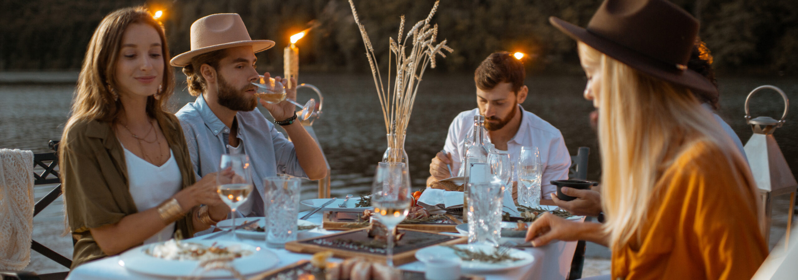 Friends dining on the beach at dusk adults dine outdoors near water at sunset 2026 09 24 07 43 46 utc cr scaled